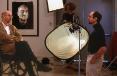 Photo of Chuck Close being interviewed by Doug vanderHoof surrounded by lighting equipment